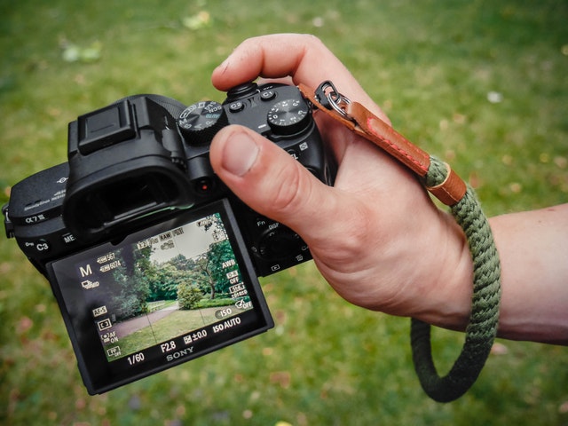 a man holding a camera and wearing green wrist strap, one of the best camera straps to buy